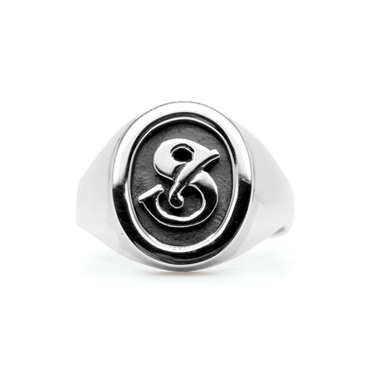 A signet ring made of silver, featuring an embossed 'S' on a round band.