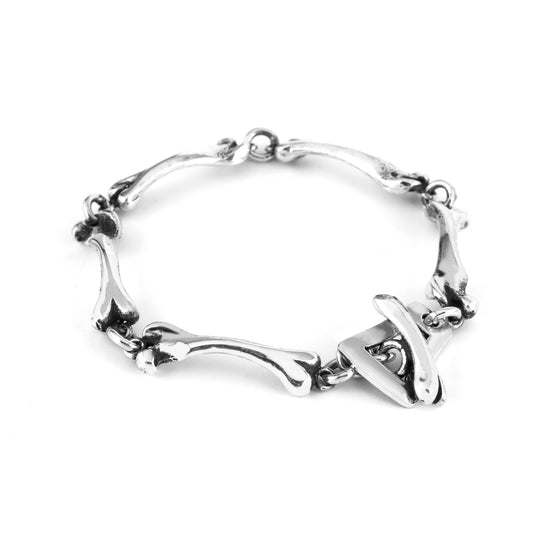 A sterling silver bracelet with a skull and bone design, displayed on a chain.