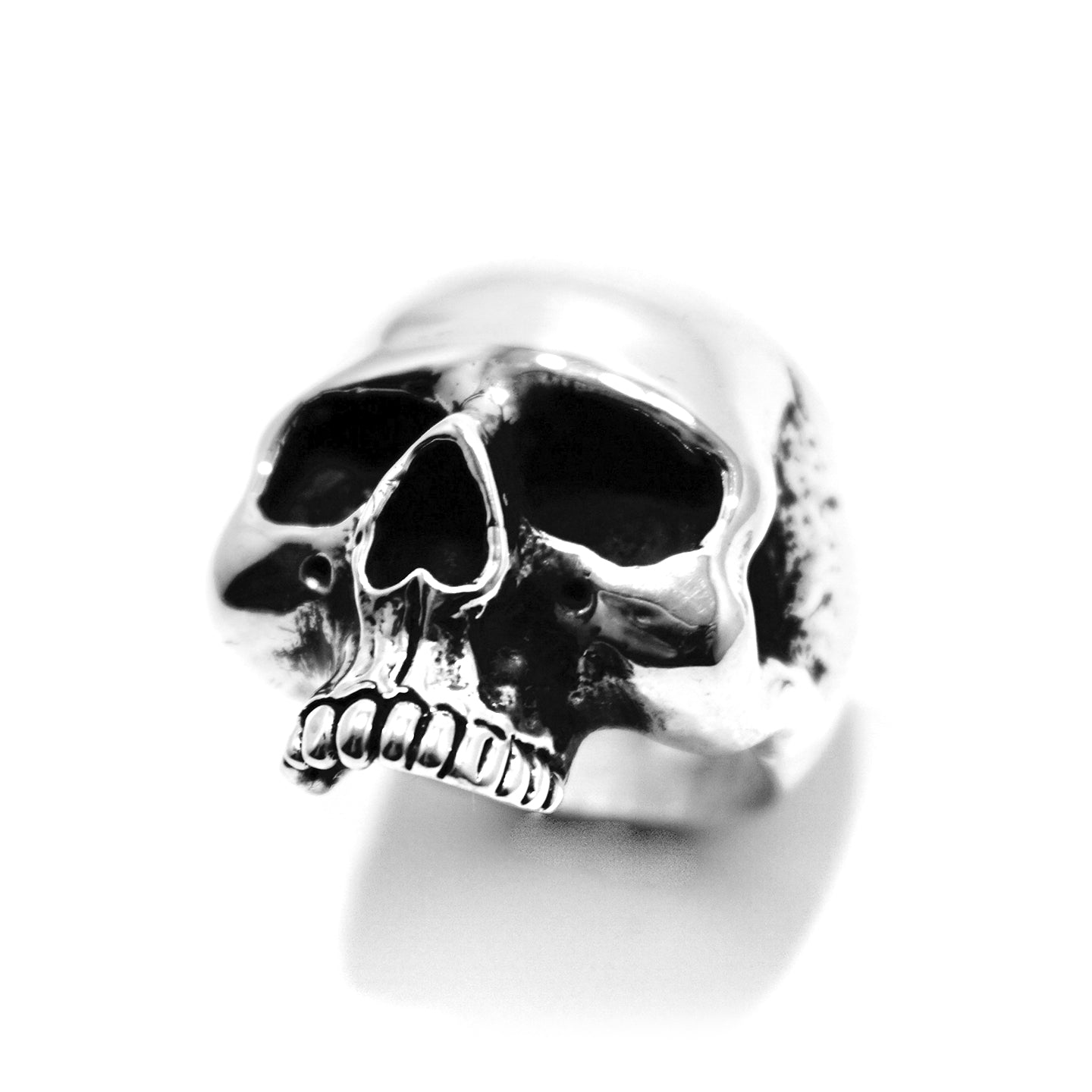 A silver ring featuring a skull design on top, set against a plain background.